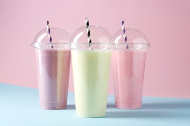 Photo of Tasty milkshakes in plastic cups on color background