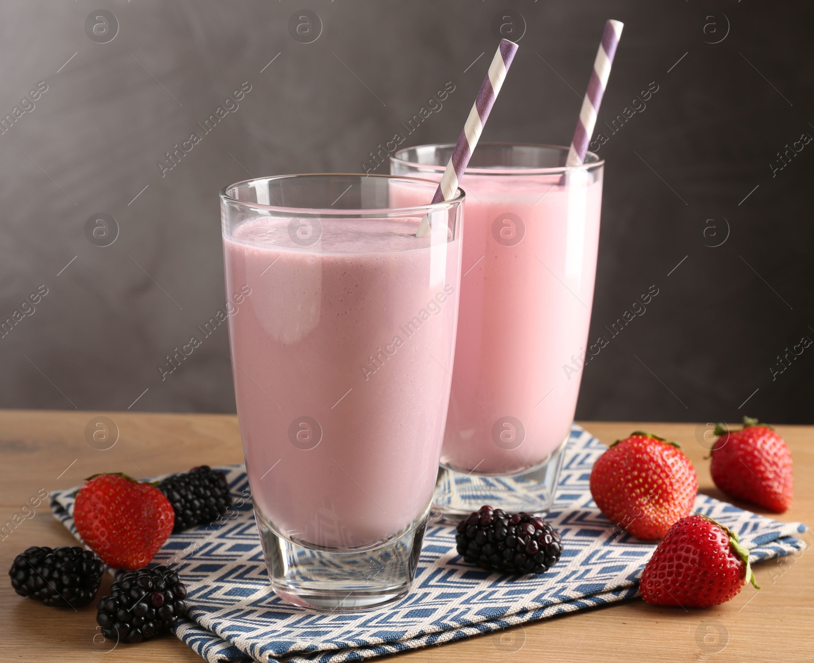 Photo of Tasty milkshakes in glasses and berries on wooden table