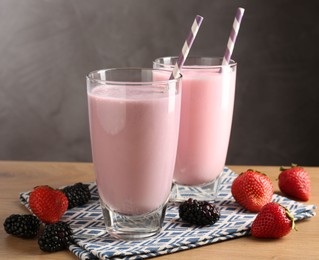 Photo of Tasty milkshakes in glasses and berries on wooden table