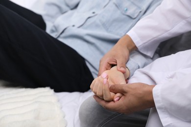 Photo of Doctor checking woman's pulse with fingers at home, closeup