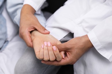 Photo of Doctor checking woman's pulse with fingers at home, closeup