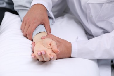 Photo of Doctor checking woman's pulse with fingers at home, closeup