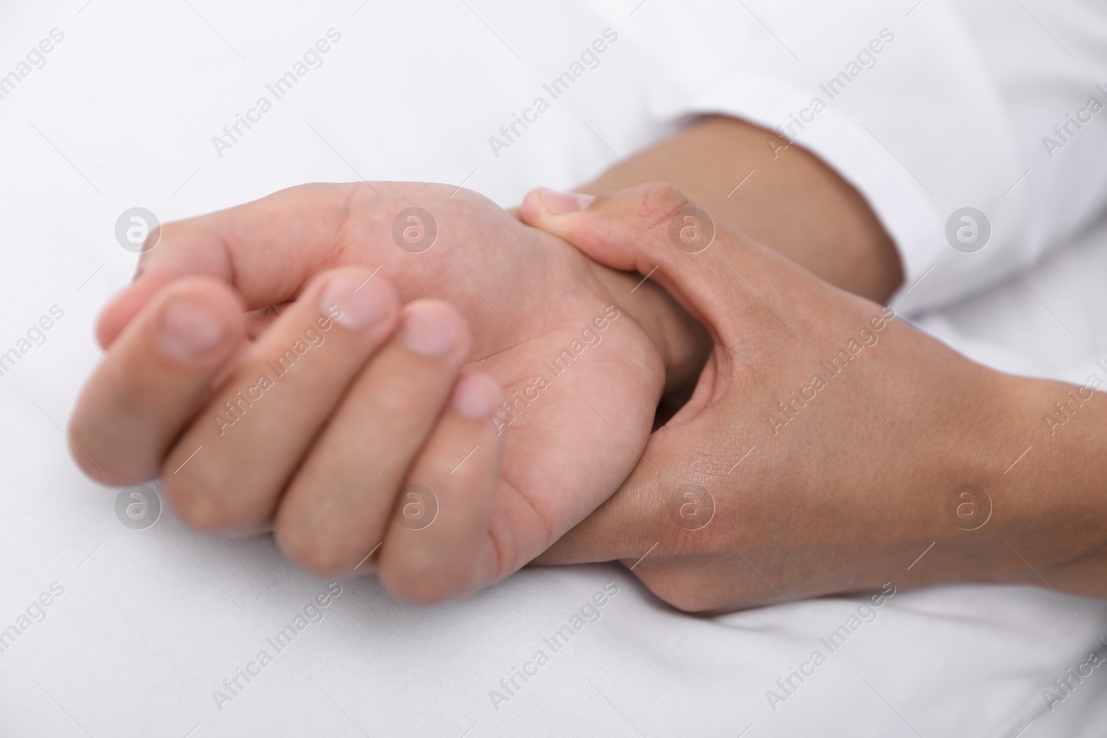 Photo of Man checking his pulse with fingers on bed, closeup