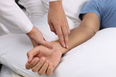 Photo of Doctor checking man's pulse with fingers at home, closeup