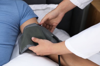 Photo of Doctor checking man's heart rate and blood pressure via sphygmomanometer at home, closeup