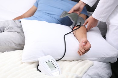 Photo of Doctor checking man's heart rate and blood pressure via sphygmomanometer at home, closeup