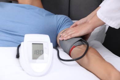 Photo of Doctor checking man's heart rate and blood pressure via sphygmomanometer at home, closeup