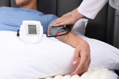 Photo of Doctor checking man's heart rate and blood pressure via sphygmomanometer at home, closeup