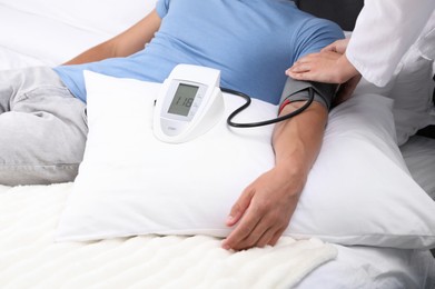 Photo of Doctor checking man's heart rate and blood pressure via sphygmomanometer at home, closeup