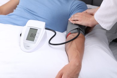 Photo of Doctor checking man's heart rate and blood pressure via sphygmomanometer at home, closeup