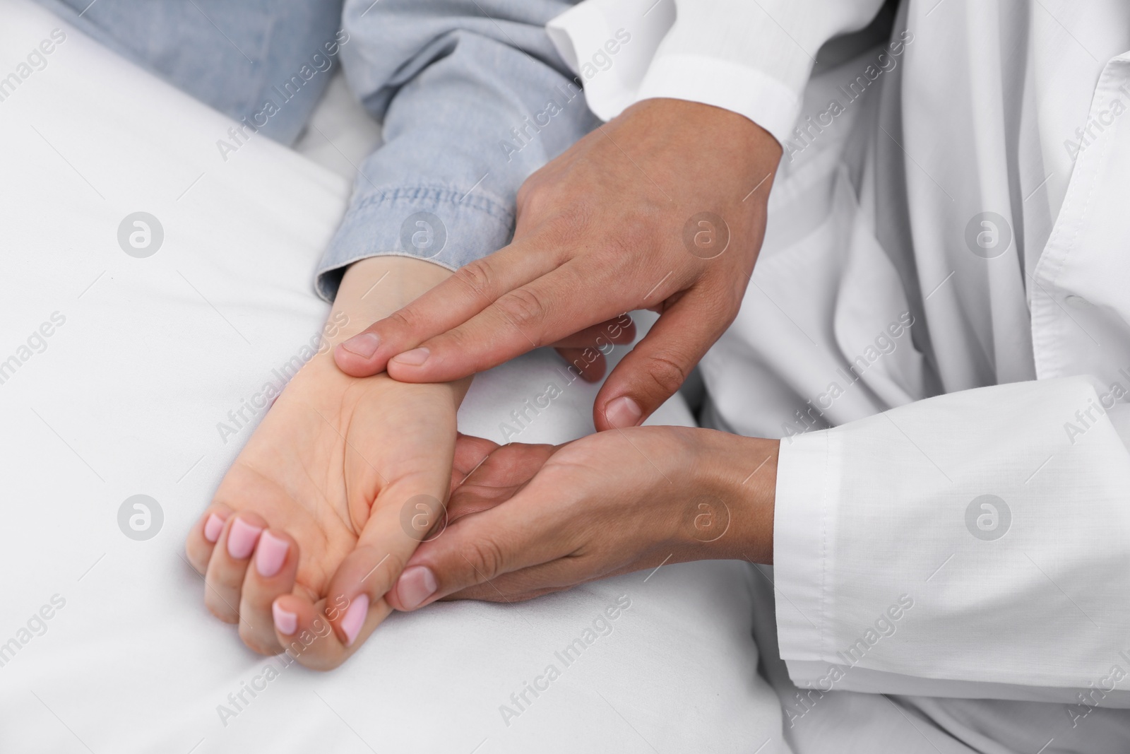 Doctor checking woman's pulse with fingers at home, closeup Photo of Doctor checking woman's pulse with fingers at home, closeup