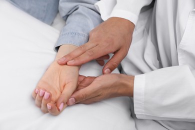 Photo of Doctor checking woman's pulse with fingers at home, closeup