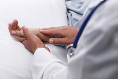Photo of Doctor checking woman's pulse with fingers at home, closeup