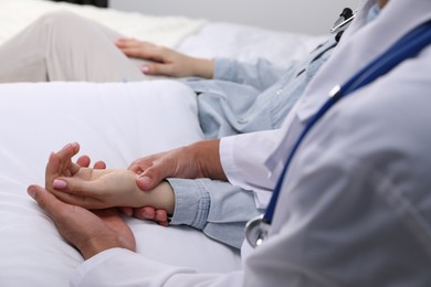 Photo of Doctor checking woman's pulse with fingers at home, closeup