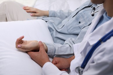 Photo of Doctor checking woman's pulse with fingers at home, closeup