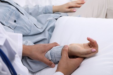 Photo of Doctor checking woman's pulse with fingers at home, closeup