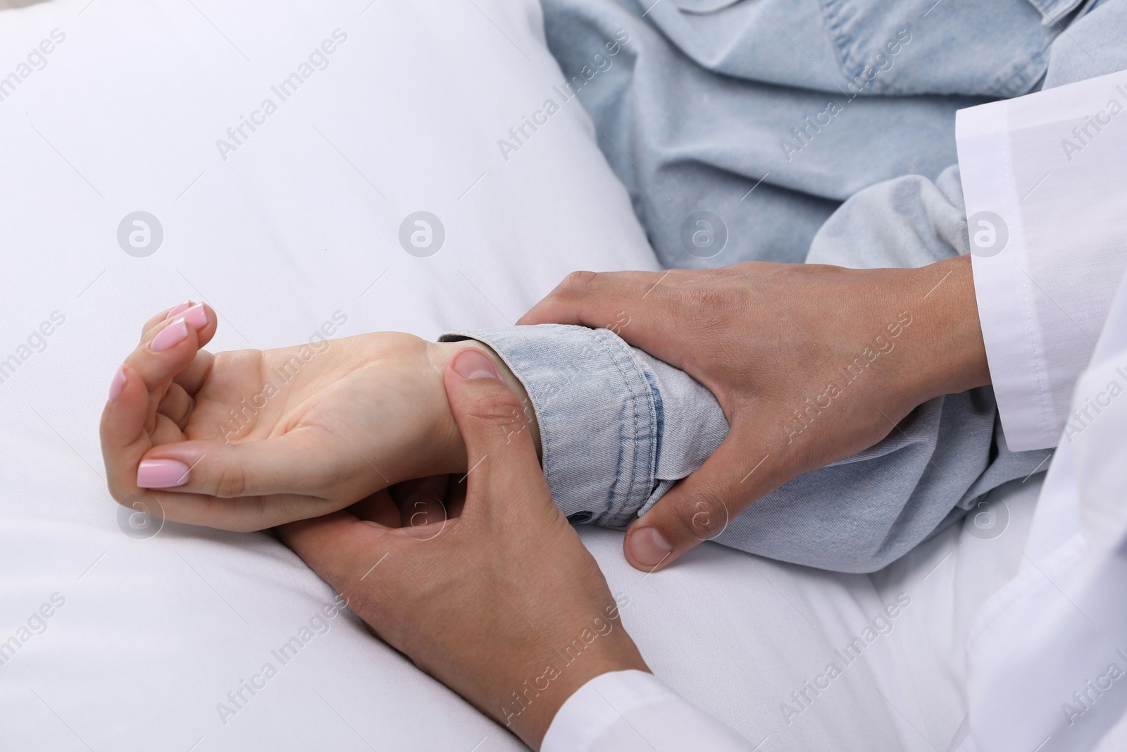 Doctor checking woman's pulse with fingers at home, closeup Photo of Doctor checking woman's pulse with fingers at home, closeup