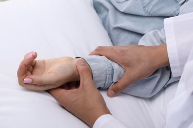 Photo of Doctor checking woman's pulse with fingers at home, closeup