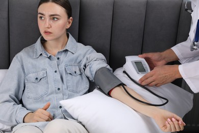 Photo of Doctor checking woman's heart rate and blood pressure via sphygmomanometer at home, closeup