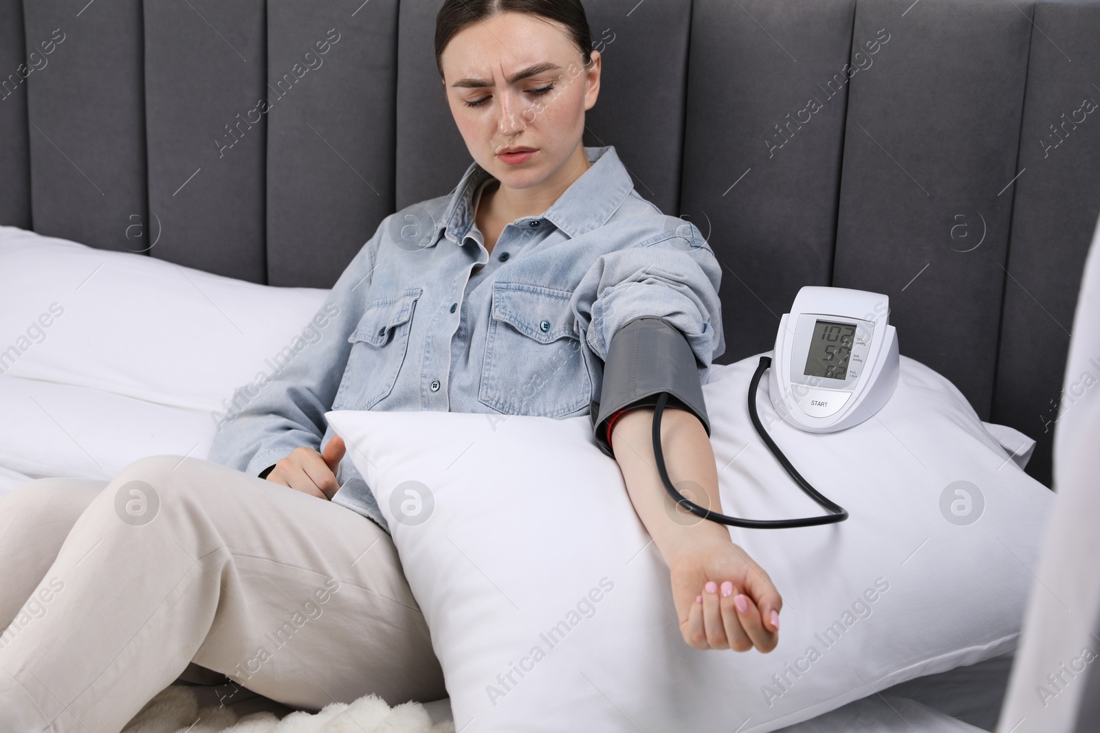 Woman checking her heart rate and blood pressure via sphygmomanometer on bed at home Photo of Woman checking her heart rate and blood pressure via sphygmomanometer on bed at home