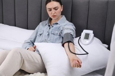 Photo of Woman checking her heart rate and blood pressure via sphygmomanometer on bed at home