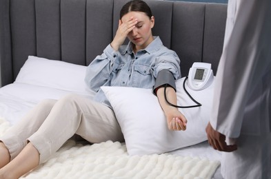 Photo of Doctor checking woman's heart rate and blood pressure via sphygmomanometer at home, closeup