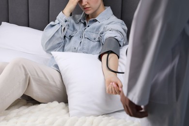 Photo of Doctor checking woman's heart rate and blood pressure via sphygmomanometer at home, closeup