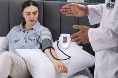 Photo of Doctor checking woman's heart rate and blood pressure via sphygmomanometer at home, closeup