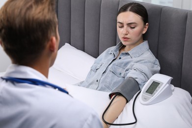 Photo of Doctor checking woman's heart rate and blood pressure via sphygmomanometer at home, closeup