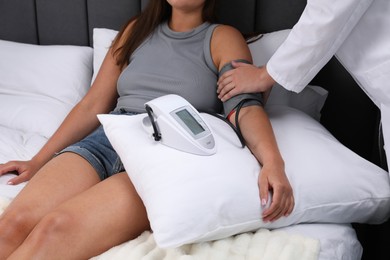 Photo of Doctor checking woman's heart rate and blood pressure via sphygmomanometer at home, closeup