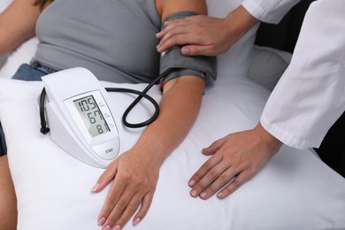 Photo of Doctor checking woman's heart rate and blood pressure via sphygmomanometer at home, closeup