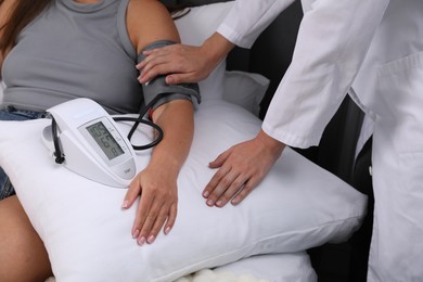 Photo of Doctor checking woman's heart rate and blood pressure via sphygmomanometer at home, closeup