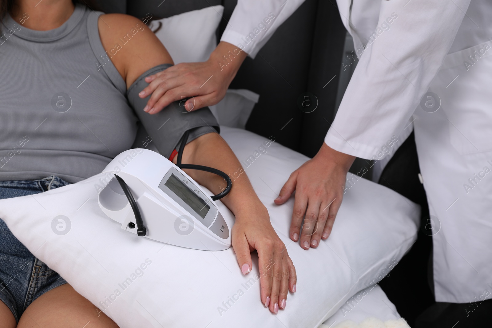 Doctor checking woman's heart rate and blood pressure via sphygmomanometer at home, closeup Photo of Doctor checking woman's heart rate and blood pressure via sphygmomanometer at home, closeup