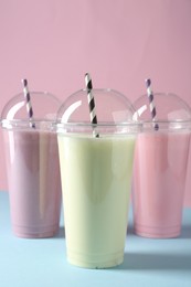 Photo of Tasty milkshakes in plastic cups on color background
