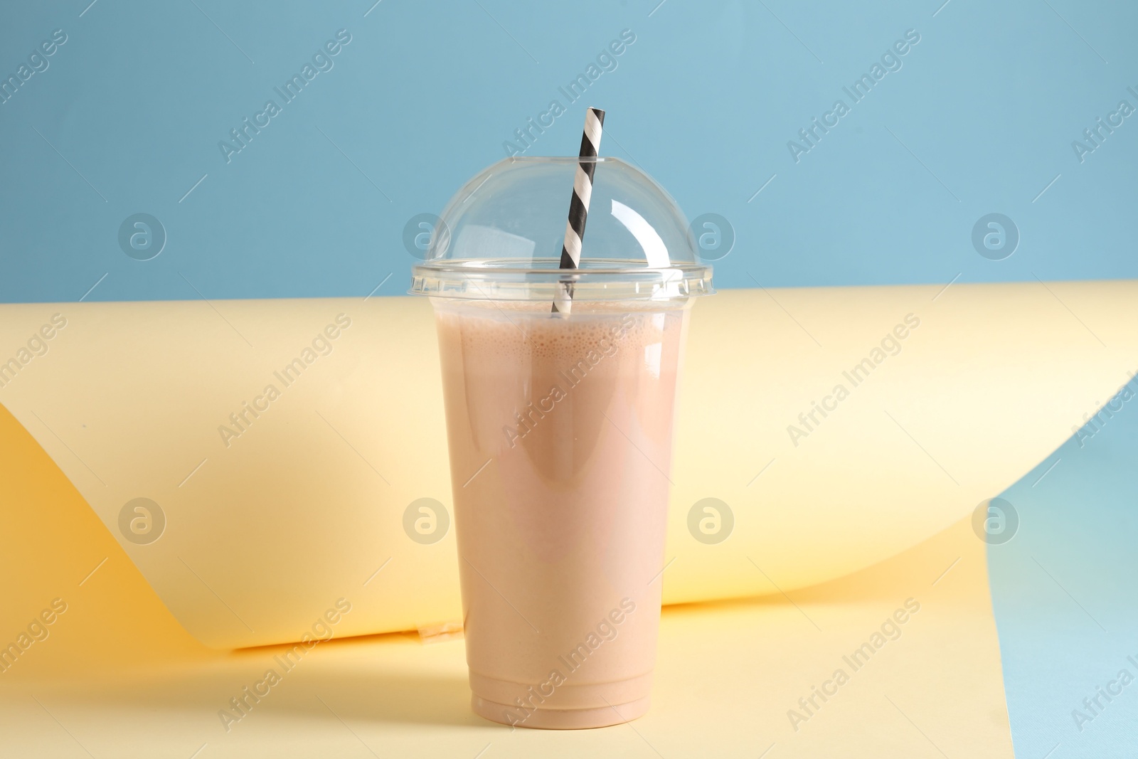 Photo of Tasty milkshake in plastic cup on color background