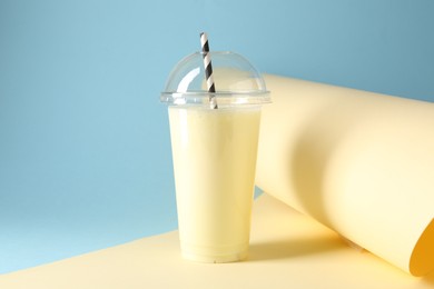 Photo of Tasty milkshake in plastic cup on color background