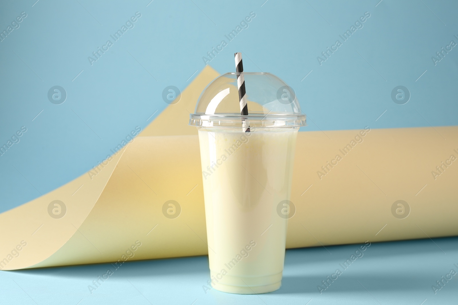 Photo of Tasty milkshake in plastic cup on color background