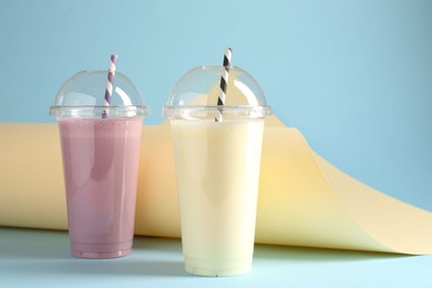 Photo of Tasty milkshakes in plastic cups on color background