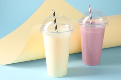 Photo of Tasty milkshakes in plastic cups on color background
