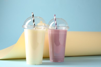 Photo of Tasty milkshakes in plastic cups on color background