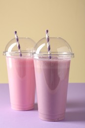 Photo of Tasty milkshakes in plastic cups on color background