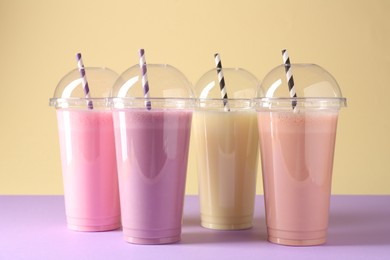 Photo of Tasty milkshakes in plastic cups on color background