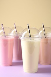 Photo of Tasty milkshakes in plastic cups on color background, closeup