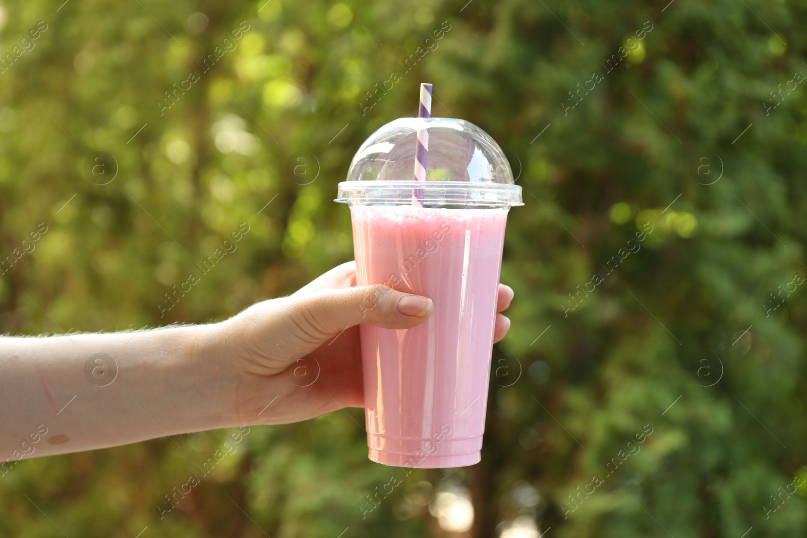 Woman holding tasty milkshake in plastic cup outdoors, closeup Photo of Woman holding tasty milkshake in plastic cup outdoors, closeup