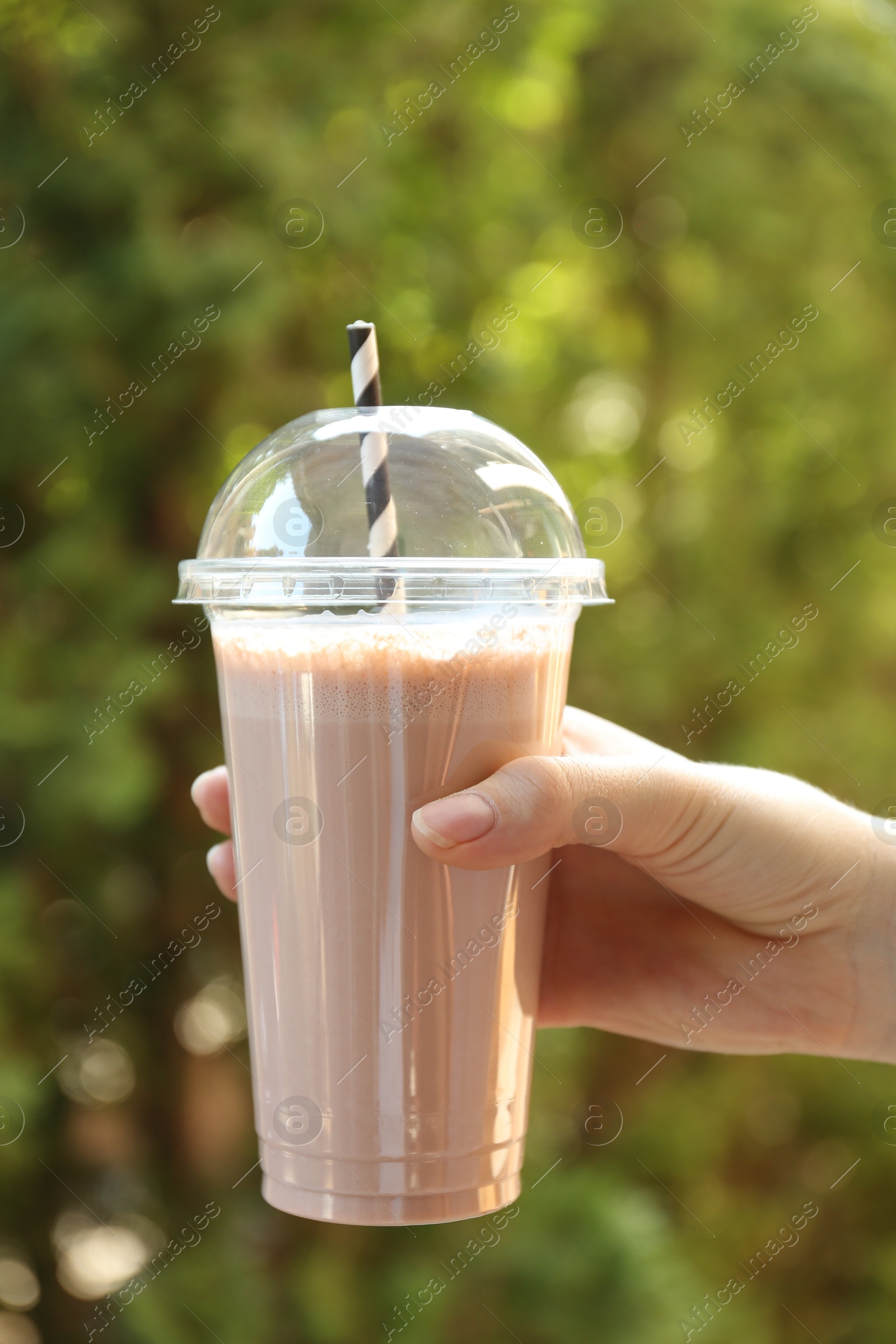 Woman holding tasty milkshake in plastic cup outdoors, closeup Photo of Woman holding tasty milkshake in plastic cup outdoors, closeup