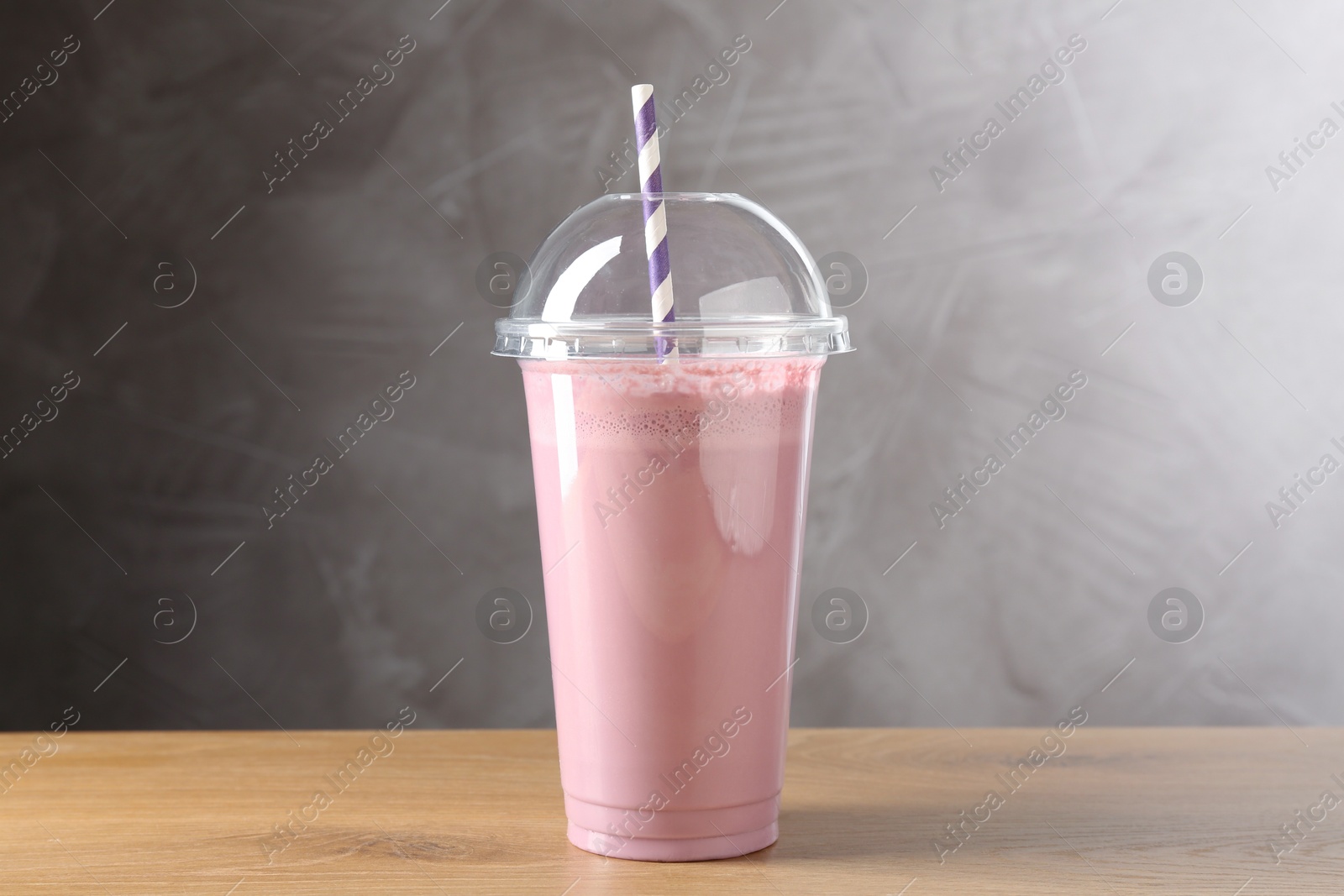 Photo of Tasty milkshake in plastic cup on wooden table