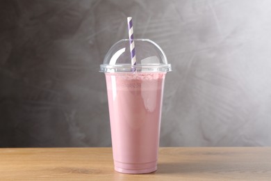 Photo of Tasty milkshake in plastic cup on wooden table