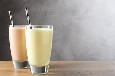 Photo of Tasty milkshakes in glasses on wooden table, space for text