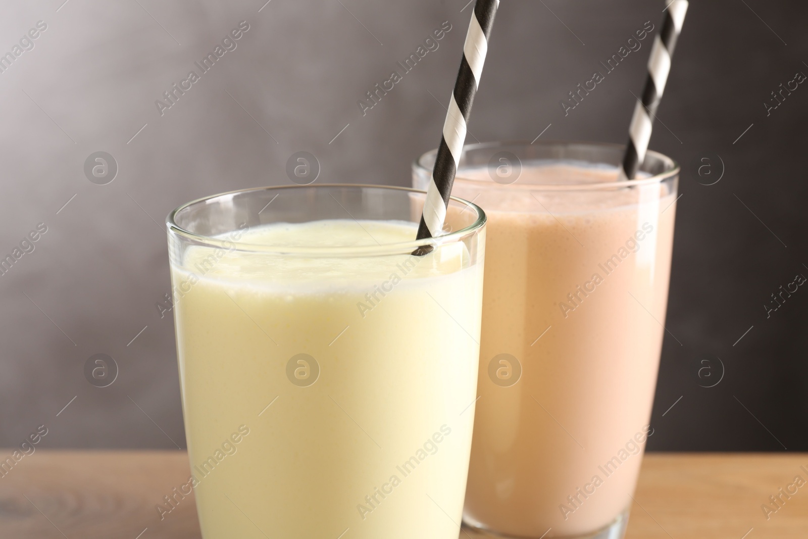 Tasty milkshakes in glasses on wooden table, closeup Photo of Tasty milkshakes in glasses on wooden table, closeup