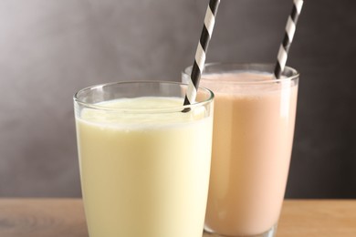 Photo of Tasty milkshakes in glasses on wooden table, closeup